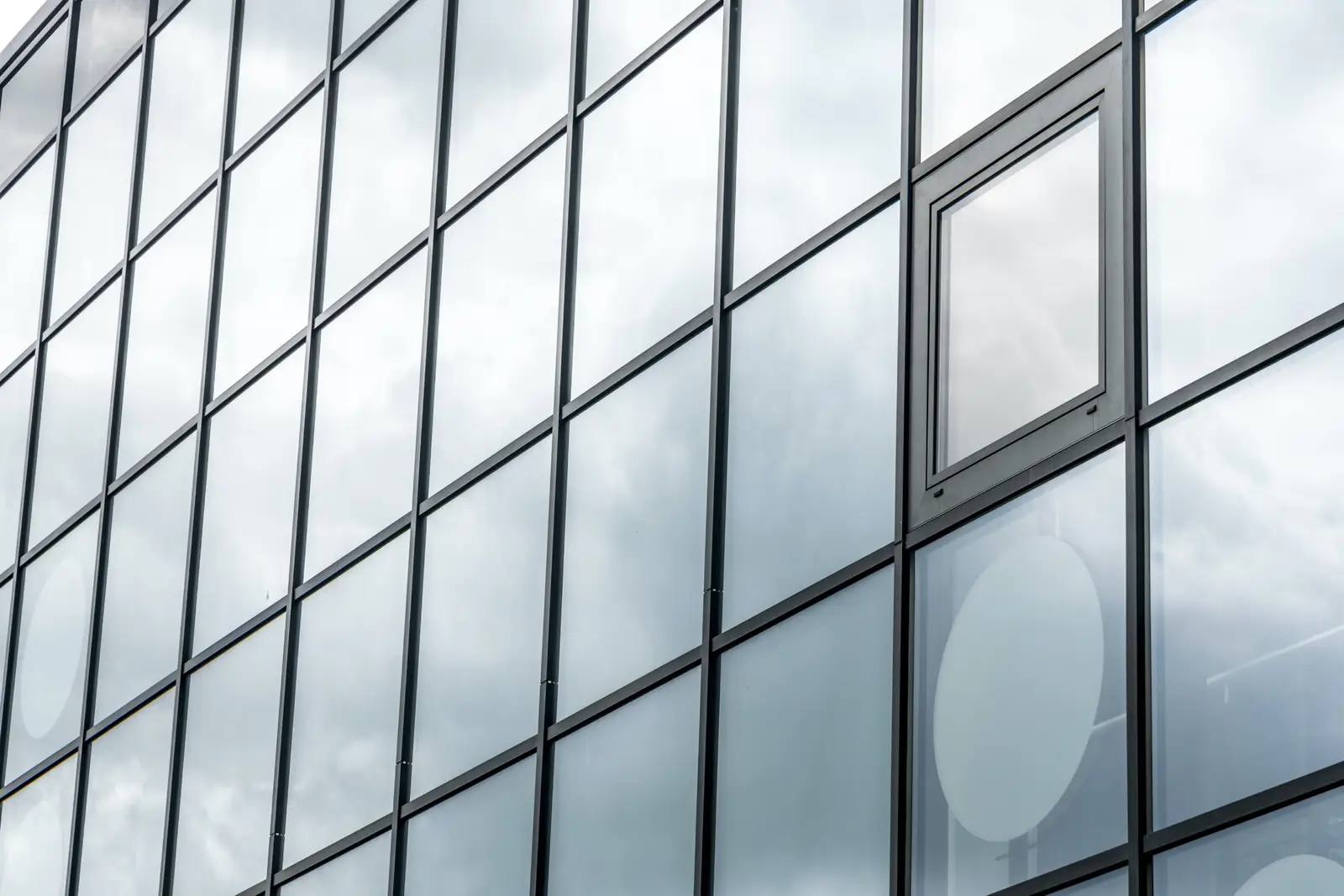 Glass curtain wall facade with aluminum mullions and an operable vent window